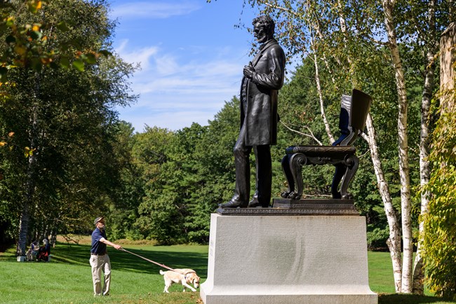 person walks dog next to statue of Lincoln