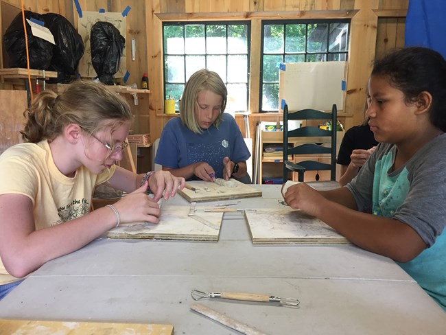 Kids around a table working on clay sculptures