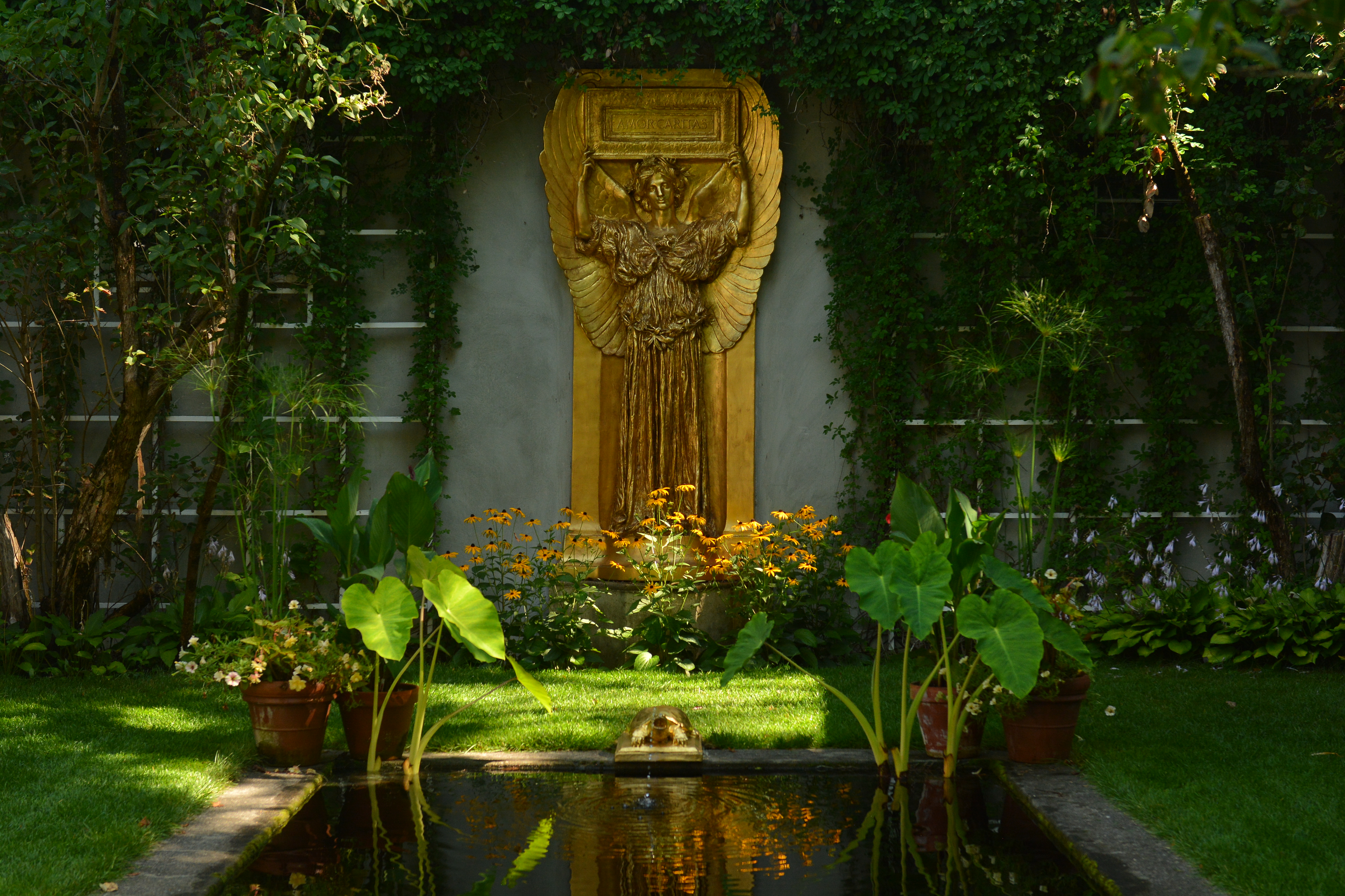 gilded sculpture of angel in front of reflecting pool