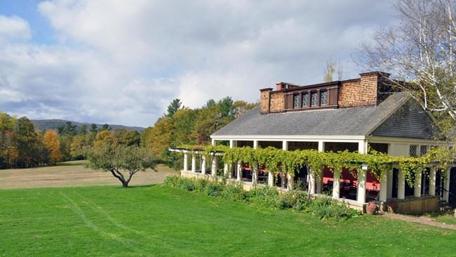 historic building with ornate roof and grape vines growing around edges with mountain landscape behind