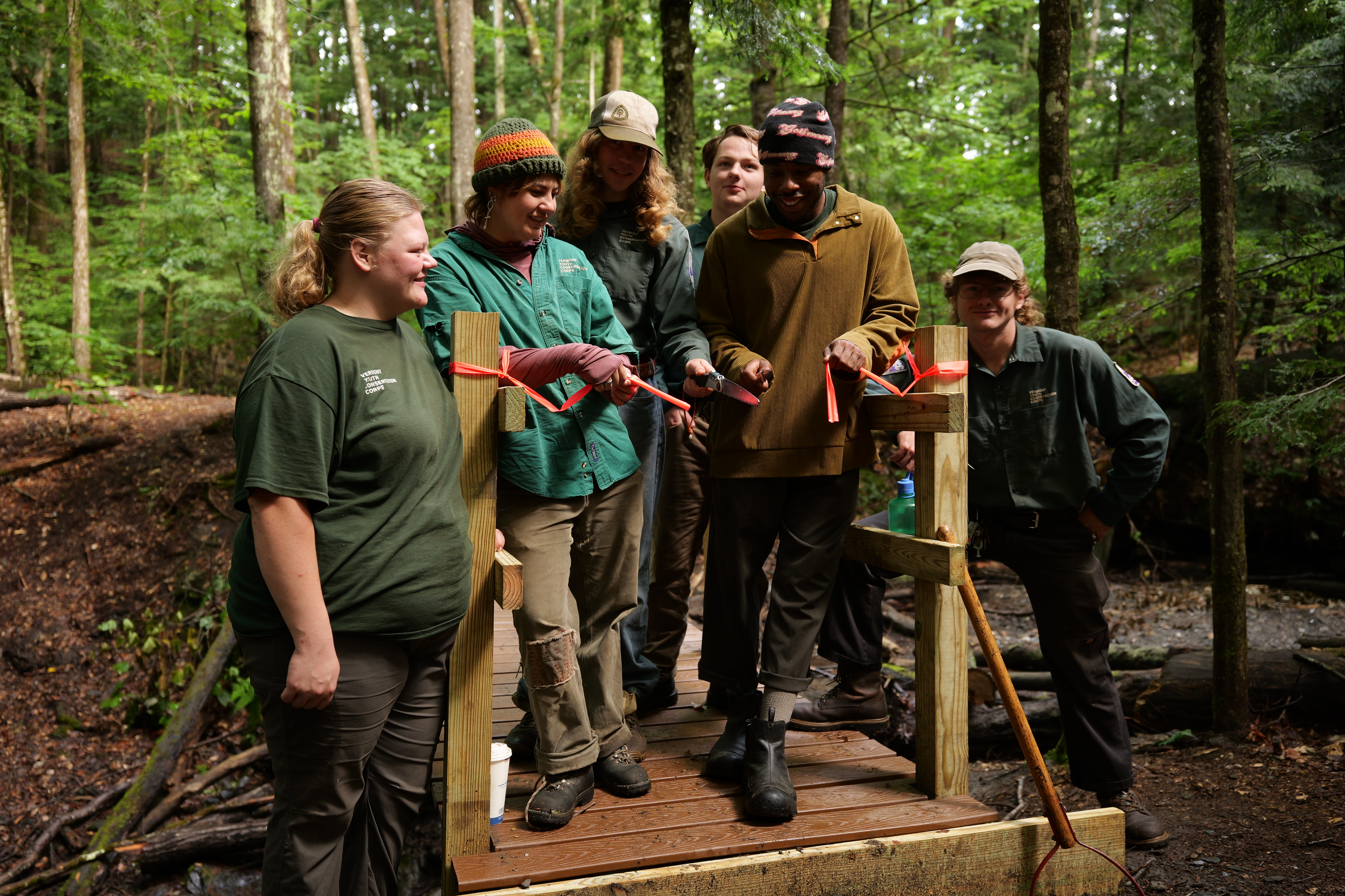 trail crew stands with newly constructed foot bridge