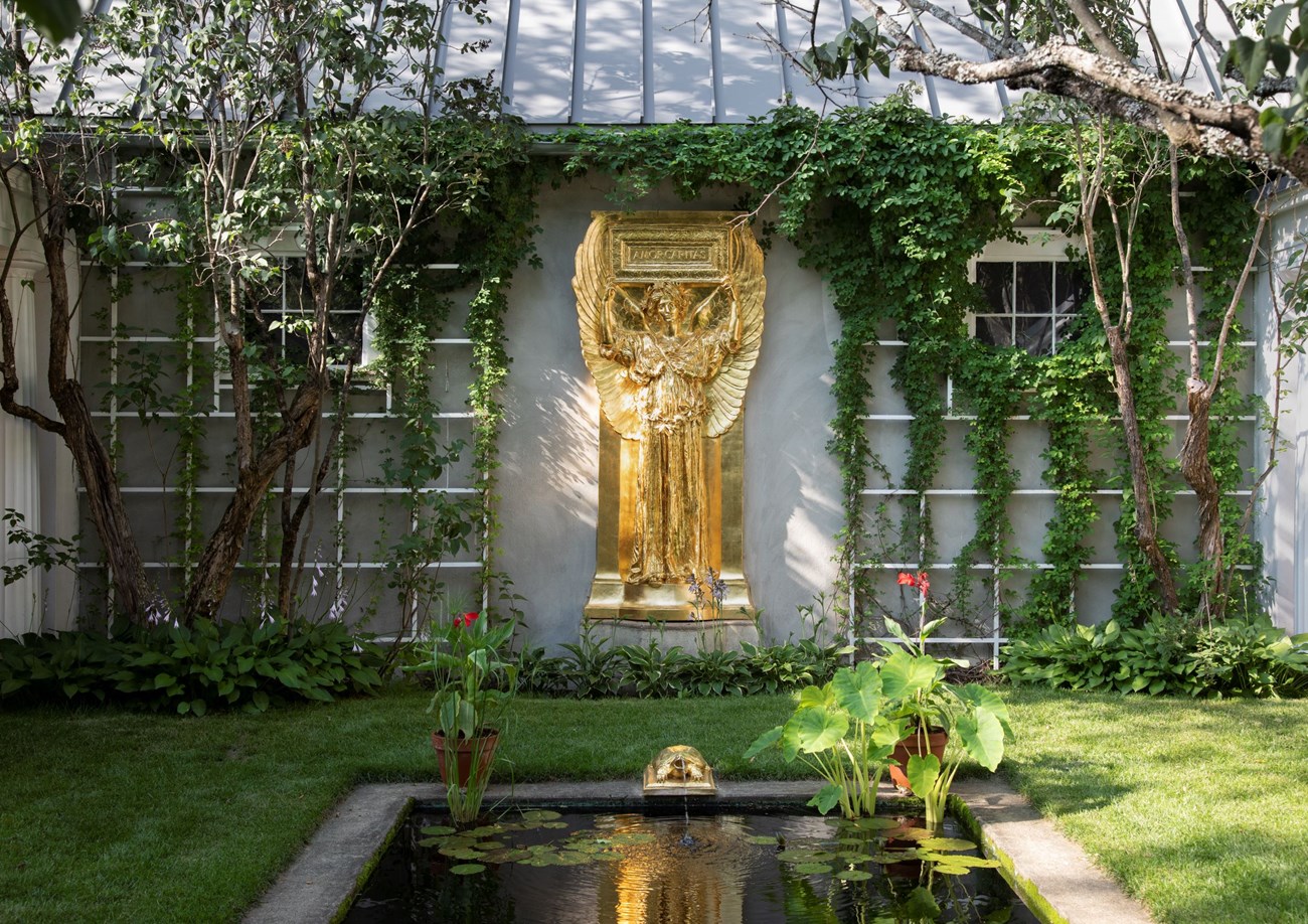gold colored sculpture of angel with reflecting pool