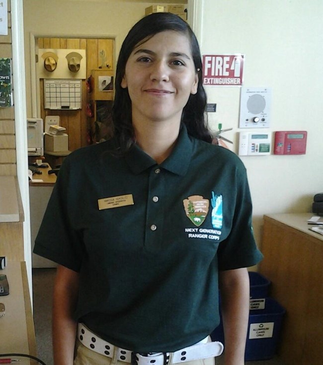 young adult in green uniform polo in visitor center