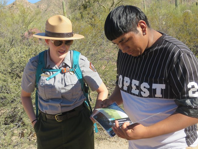 Ranger guides student through wildlife booklet during an in field educational program. Ranger guides student through wildlife booklet during an in field educational program.