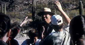 A ranger with children in a natural setting. A ranger with children in a natural setting.