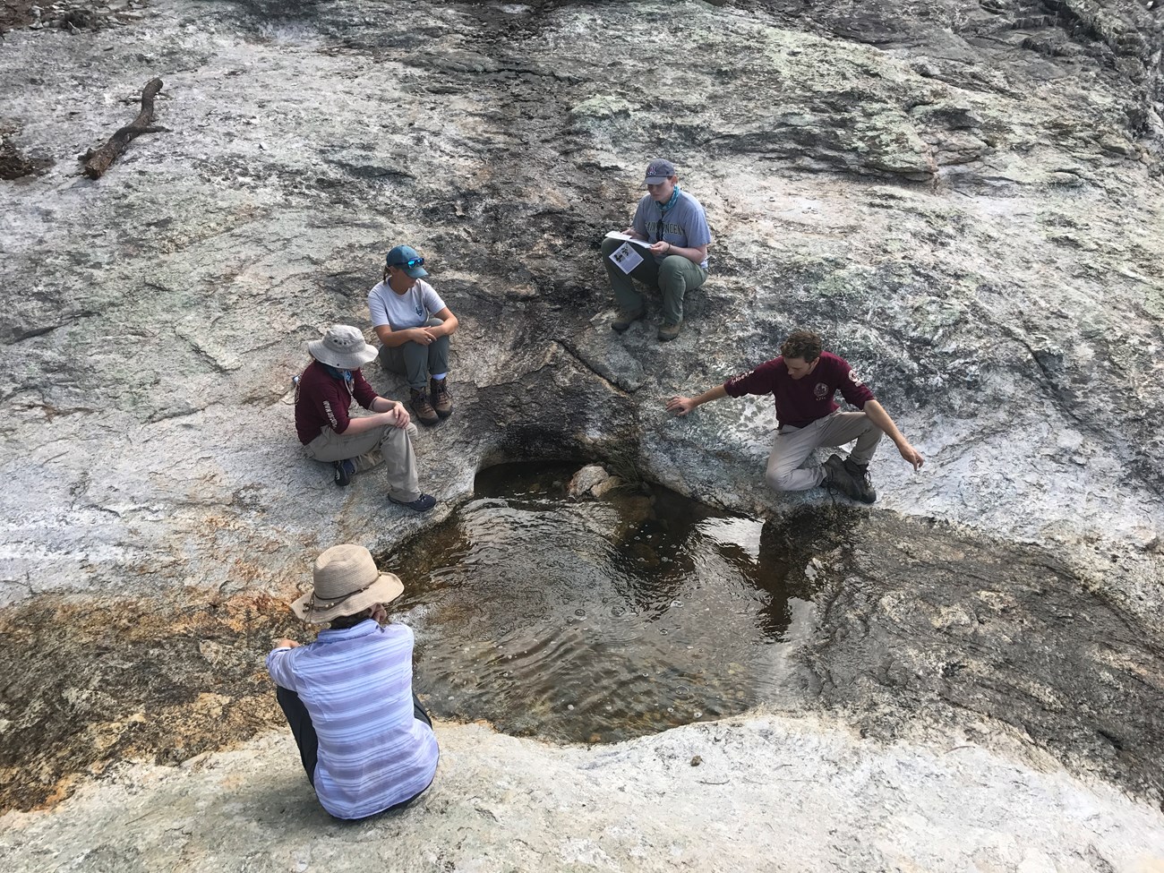 young people gathered on rocks around a desert pond