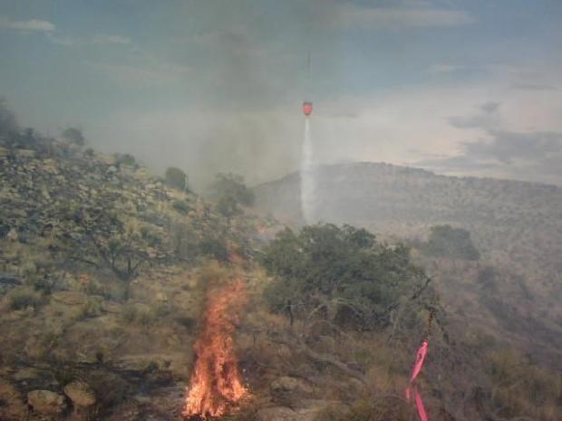 Helicopter drops a water from a bucket to help suppress the 2014 Jackalope Fire