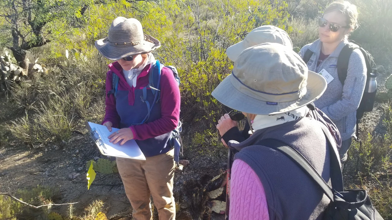 Giving instructions on how to write the coordinates A woman explaining the categories written on a clipboard to three other women