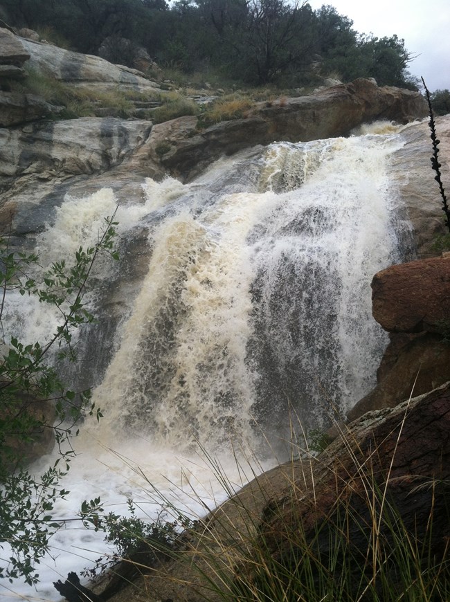 Torrent of flood water rushing over bedrock as a waterfall near Grass Shack campground
