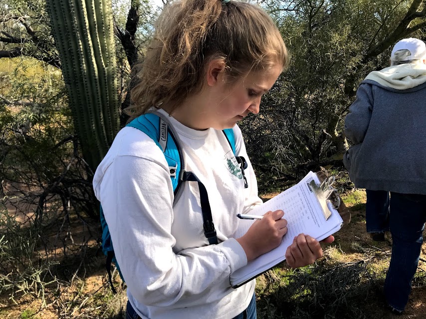 A woman writing data on a data sheet.