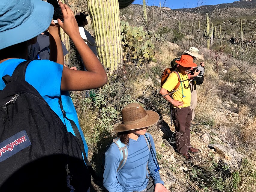 Group of volunteers on the plot. Some are sitting, standing, and taking photos.