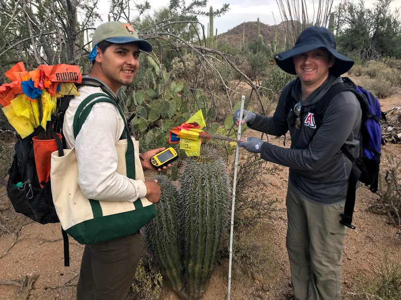 Two men smiling next to a twin saguaro