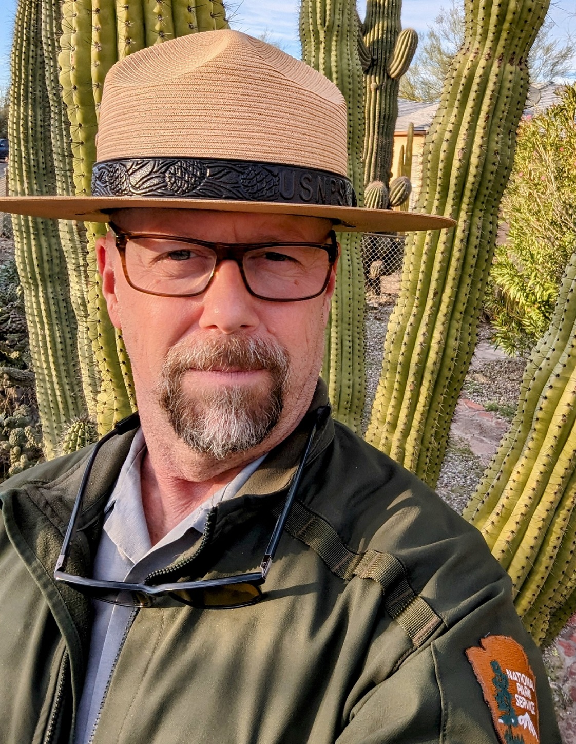Man in National Park Service uniform in front of a large cactus