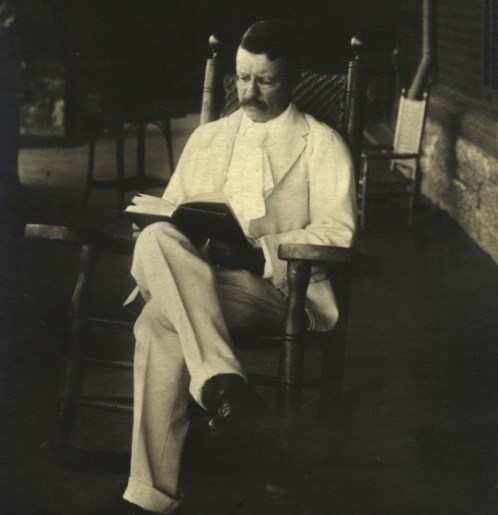 Theodore Roosevelt reading a book on his porch in 1904.