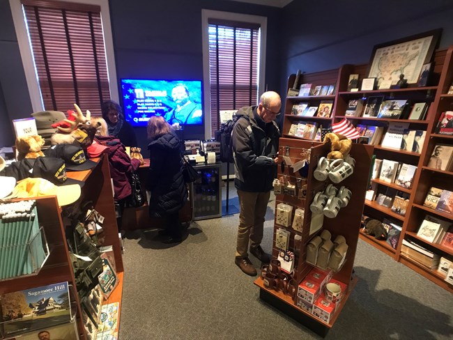 Shoppers looking at Theodore Roosevelt books and souvenirs displayed in Sagamore Hill's bookstore.