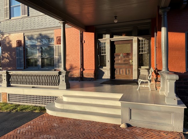 A wooden door and gray staircase under a porte cochere.