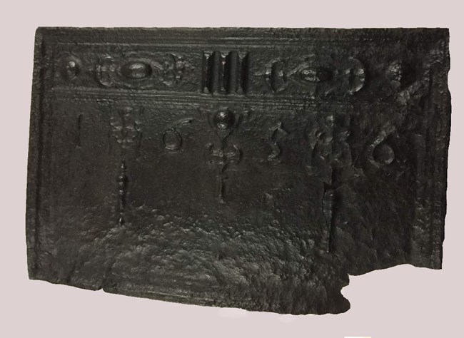 A cast iron fireback hung on fireplace meant to protect bricks from heat.