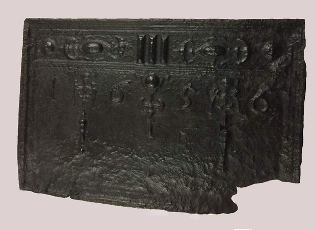 A cast iron fireback hung on fireplace meant to protect bricks from heat. A cast iron fireback hung on fireplace meant to protect bricks from heat.