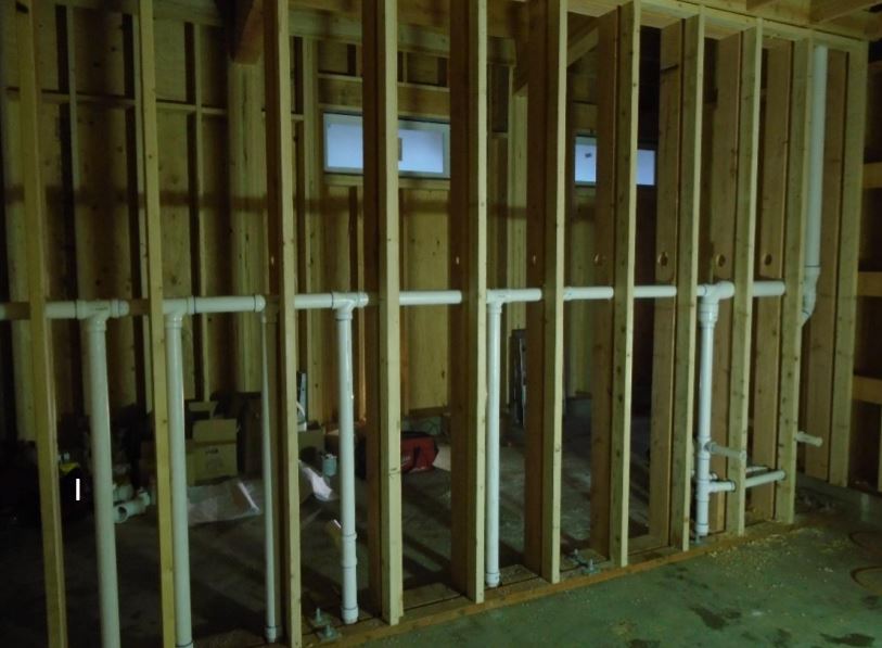 Roughed-in plumbing for restroom inside framing