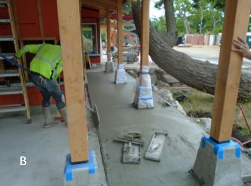 A worker finishes the concrete walkway from the restrooms to the front door