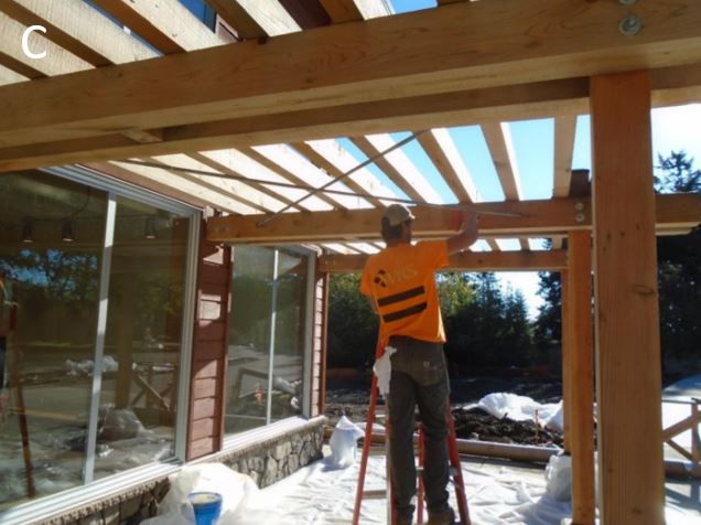 Worker re-staining trellis at entryway