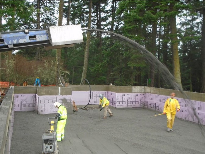 Conveyor belt distributing gravel overhead while construction works work below on distributing and compacting the gravel evenly.