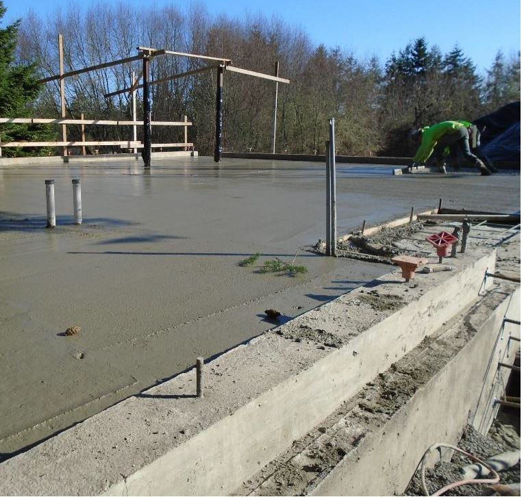 A worker uses a wood board to level wet concrete