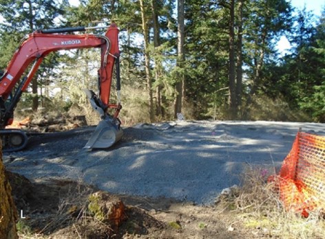 A backhoe levels gravel at the site of the picnic area