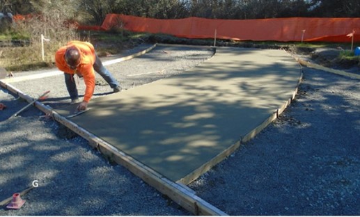 A worker smooths poured concrete poured at the interpretive plaza