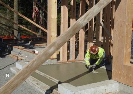 Entryway concrete finishing A worker smooths concrete that has been poured in the entryway