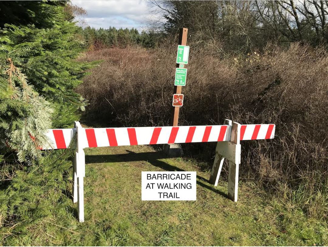 A barricade is placed across the trail to prevent pedestrian traffic