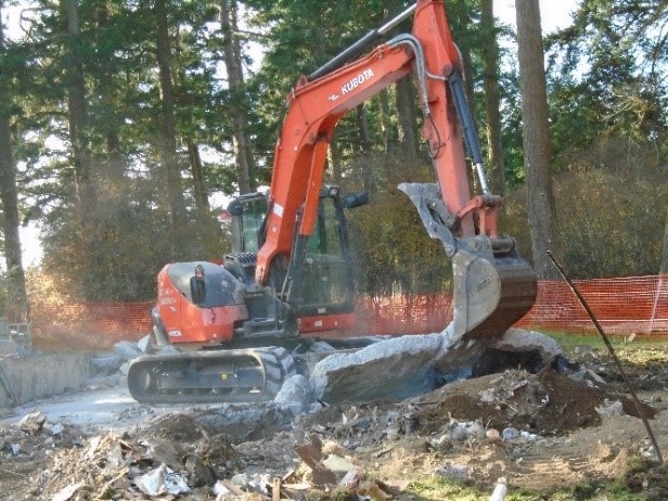 Excavation of old cement slab being removed by heavy machine equipment