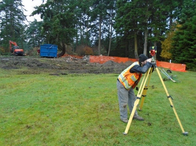 A person sighting a reflector to set up surveying locations for the new visitor center layout 