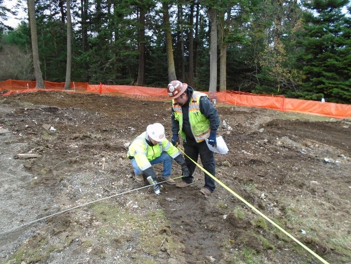 Two construction workers surveyed newly excavated land to start marking the new visitor center footprint