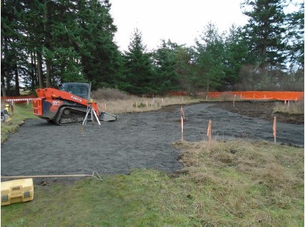 Heavy machinery is used to spread gravel in the newly excavated site