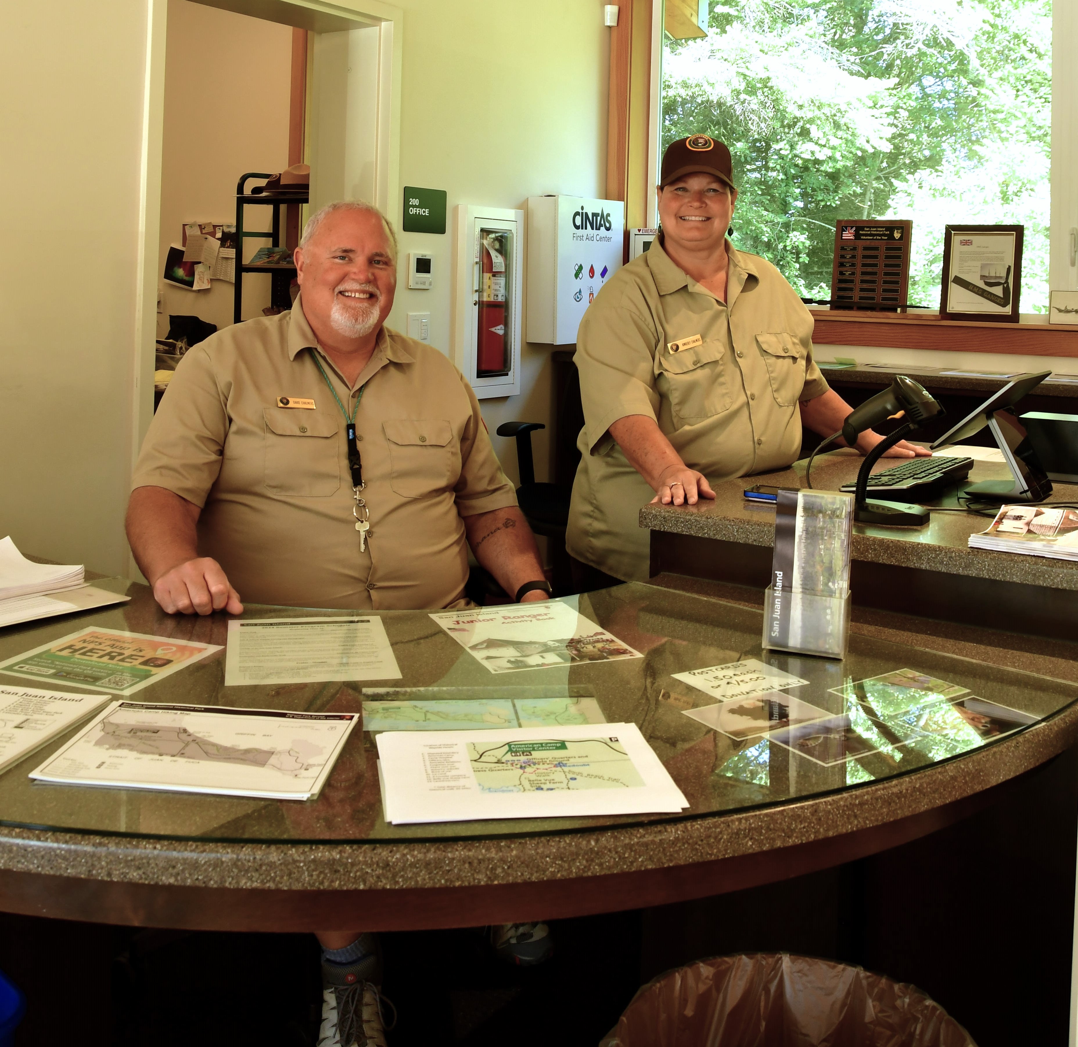 Visitor center volunteers in uniform standing behind a desk.