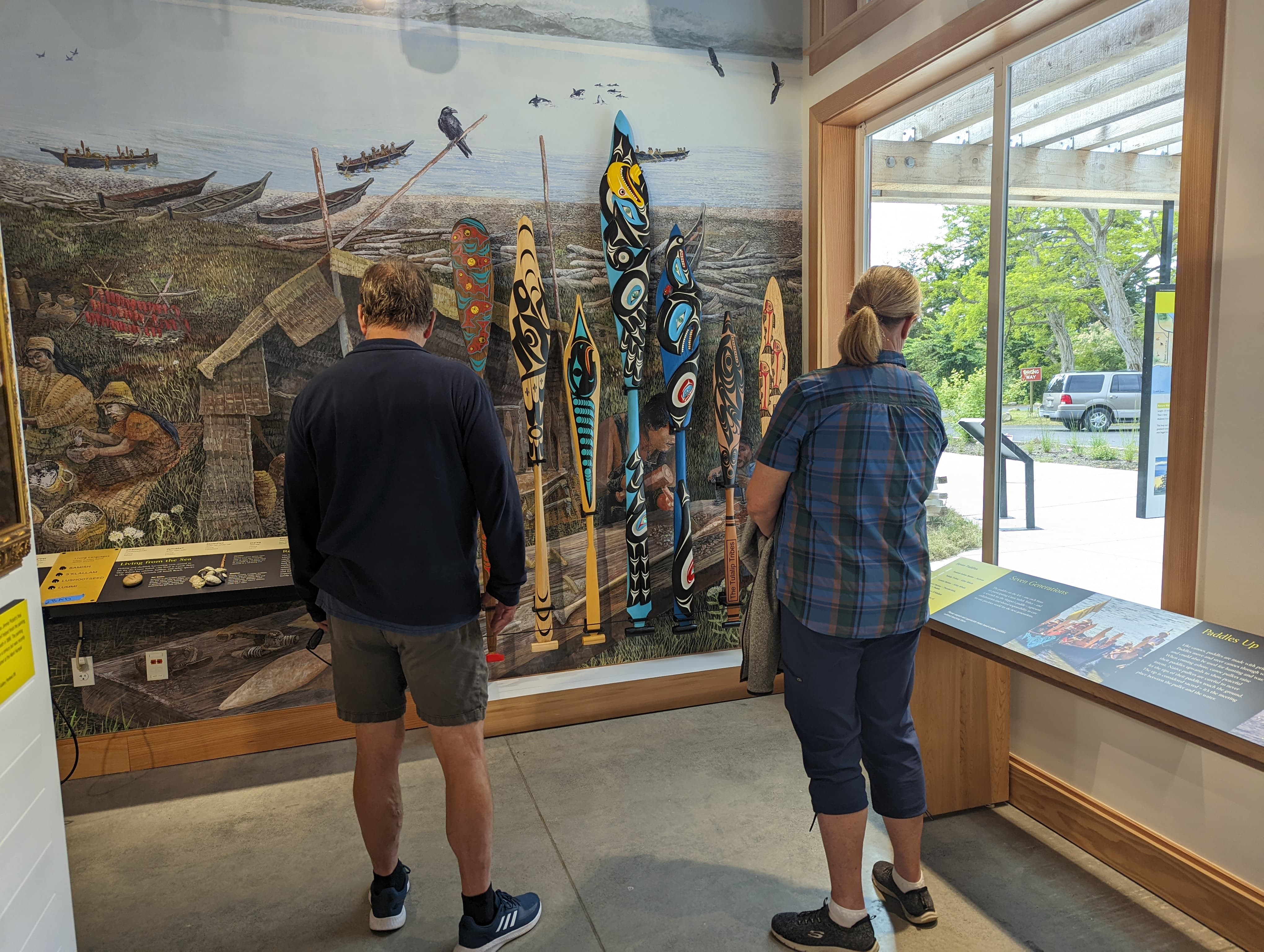 Color photograph of two people examining a display of colorful paddles.