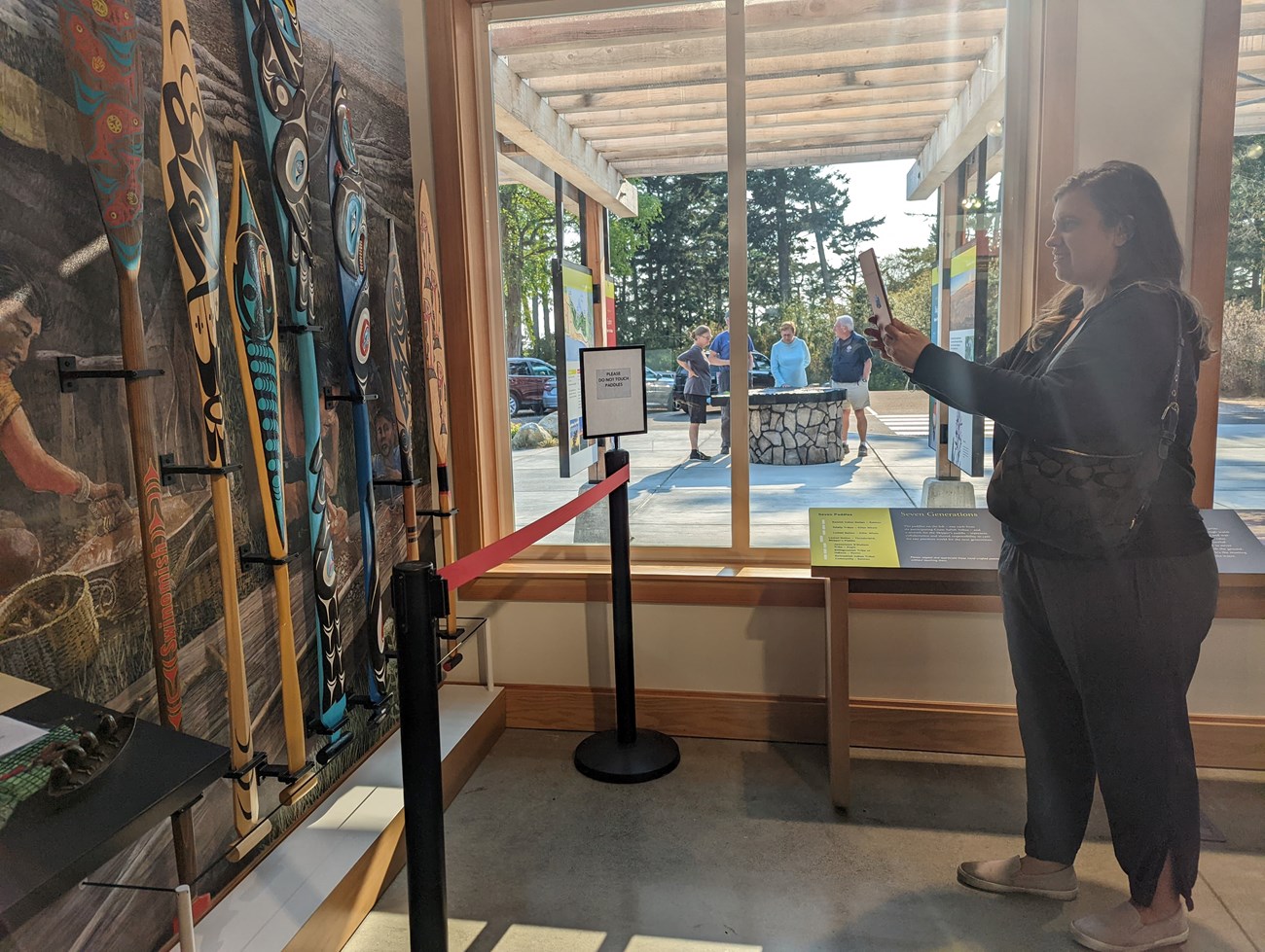 color photo of a person looking at a colorful display of artistically made kayak paddles