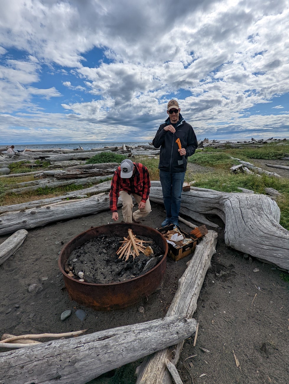 two people building a campfire in a fire pit