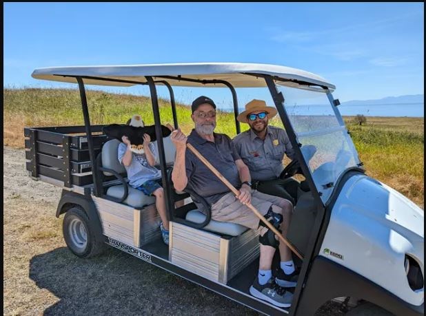 photo of a park ranger in sunglasses driving a visitor across a scenic landscape