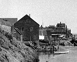 An historic photograph of Pedrick Store House in its original place on Tucker's wharf
