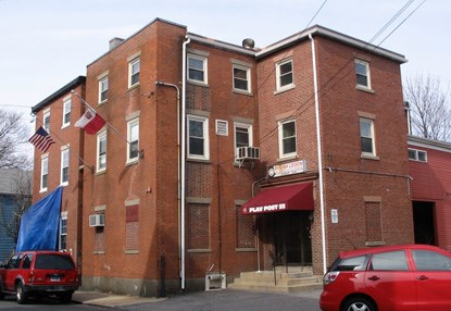 A large brick three story building, with a flat roof and wings jutting out at right angles A large brick three story building, with a flat roof and wings jutting out at right angles