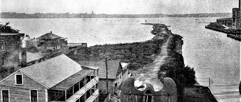 black and white photo of wharf extending into harbor