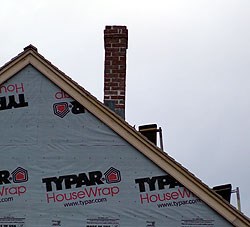 Small brick chimney sticking out of the roof of Pedrick Store House