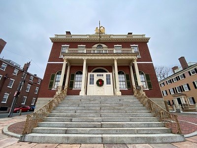 A large brick building with decorative metal and woodwork. A large sign says " CUSTOM HOUSE"