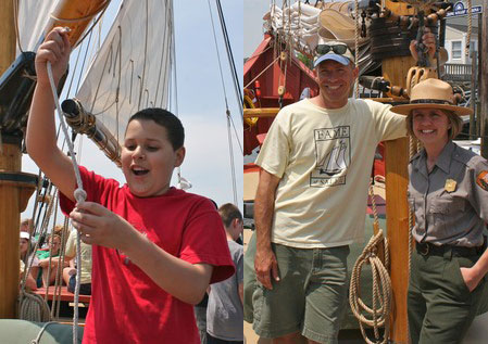 Child Pulls on Ship Line and Program Organizers Pose for Photo