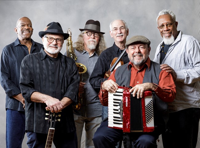 A group of six male musicians pose for a picture with their instruments