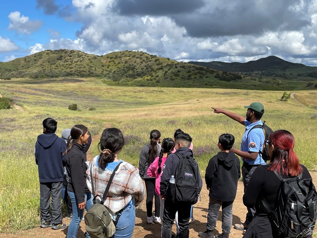Intern takes a group of students on hike and points out features.