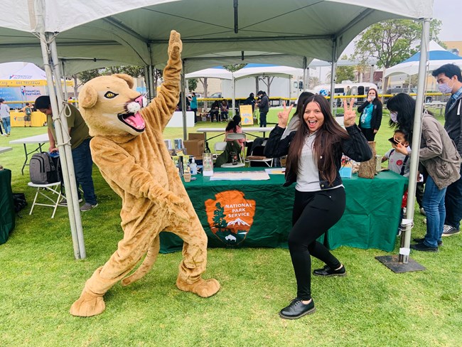 Individual at event positing with Mountain Lion Mascot