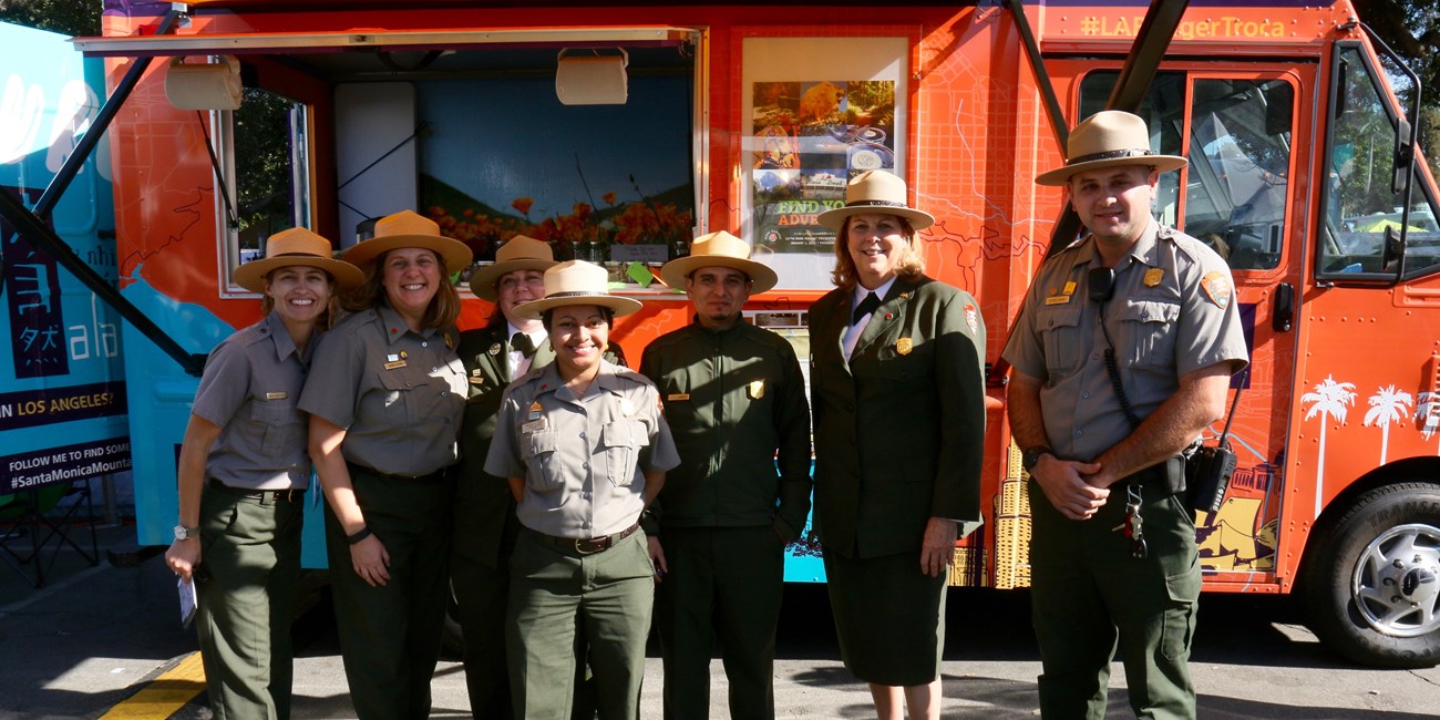 Rangers stand in front of a bright orange food truck.